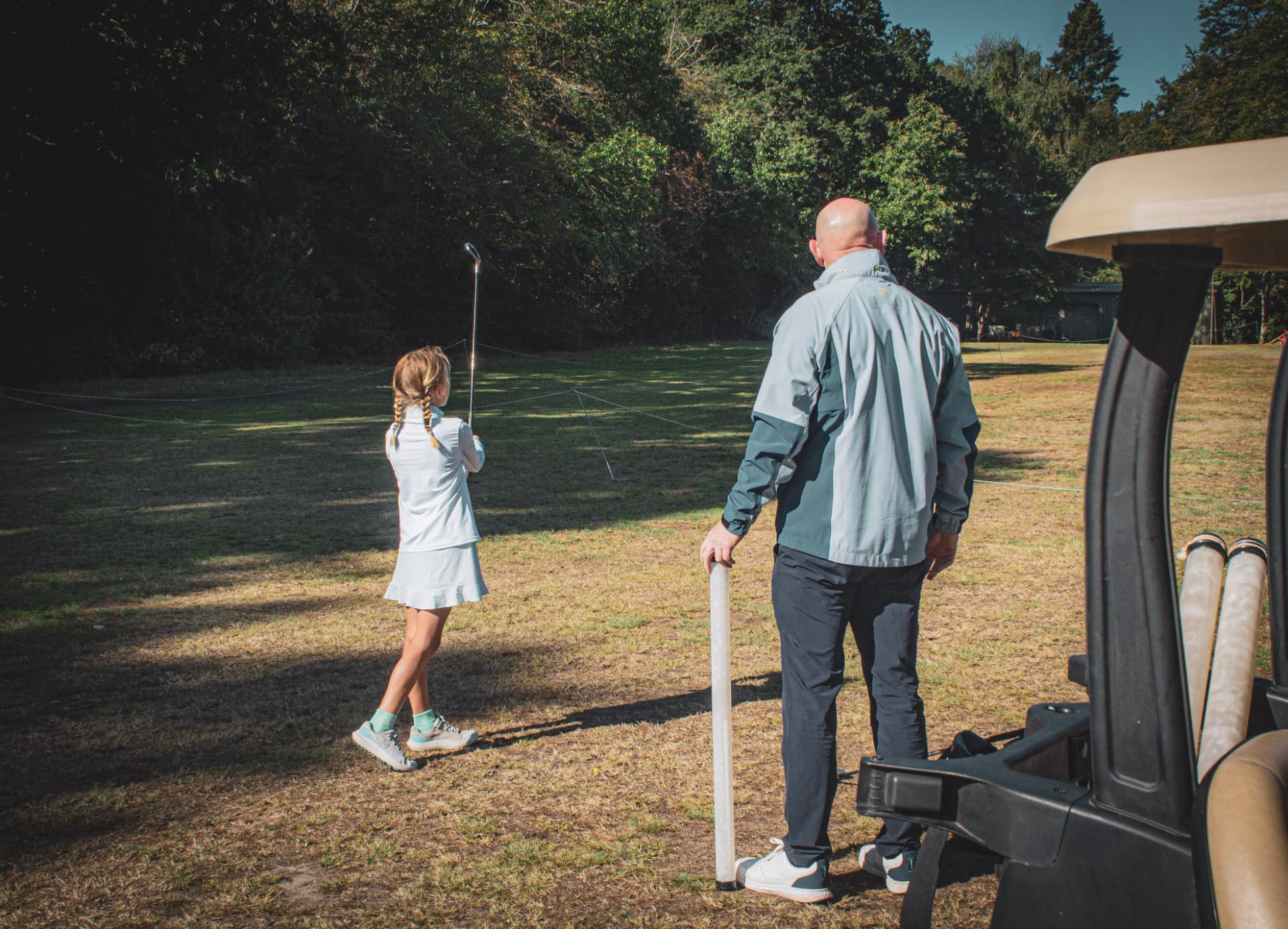 Kevin Evans coaching a junior golfer from beside a golf cart